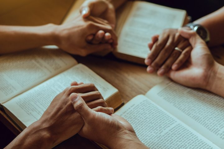 Christian family spending time to reading and study bible in home and pray together.