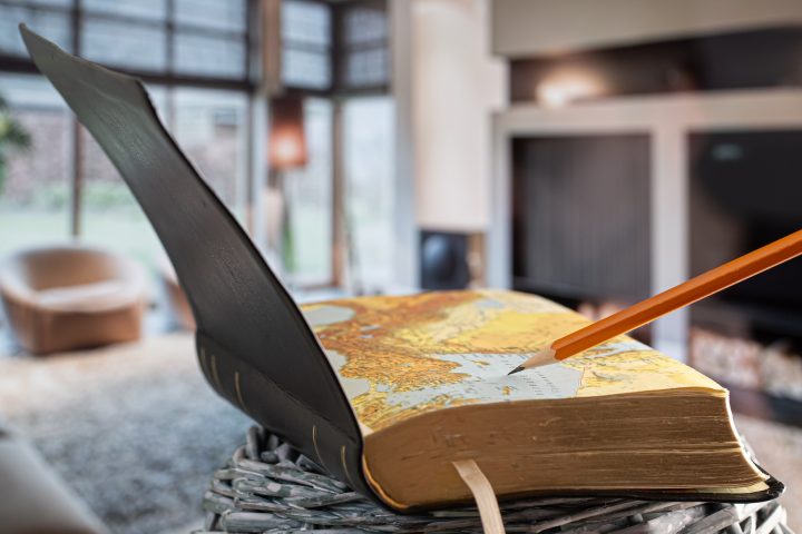 Open book Bible with pencil, on the background of the living room.