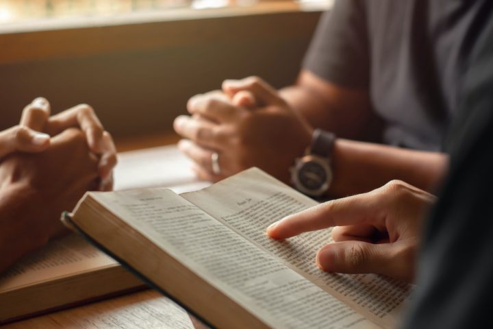 young man reading bible with friends who are praying to God Join the cell group at the church.